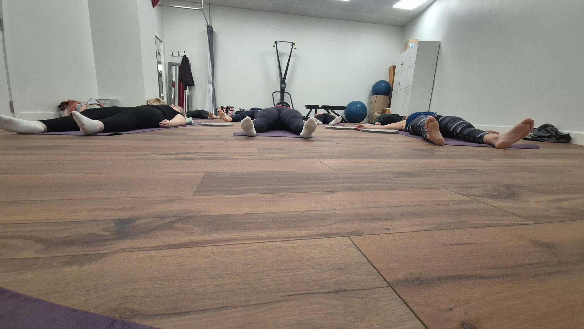 A small group resting in savasana on yoga mats together